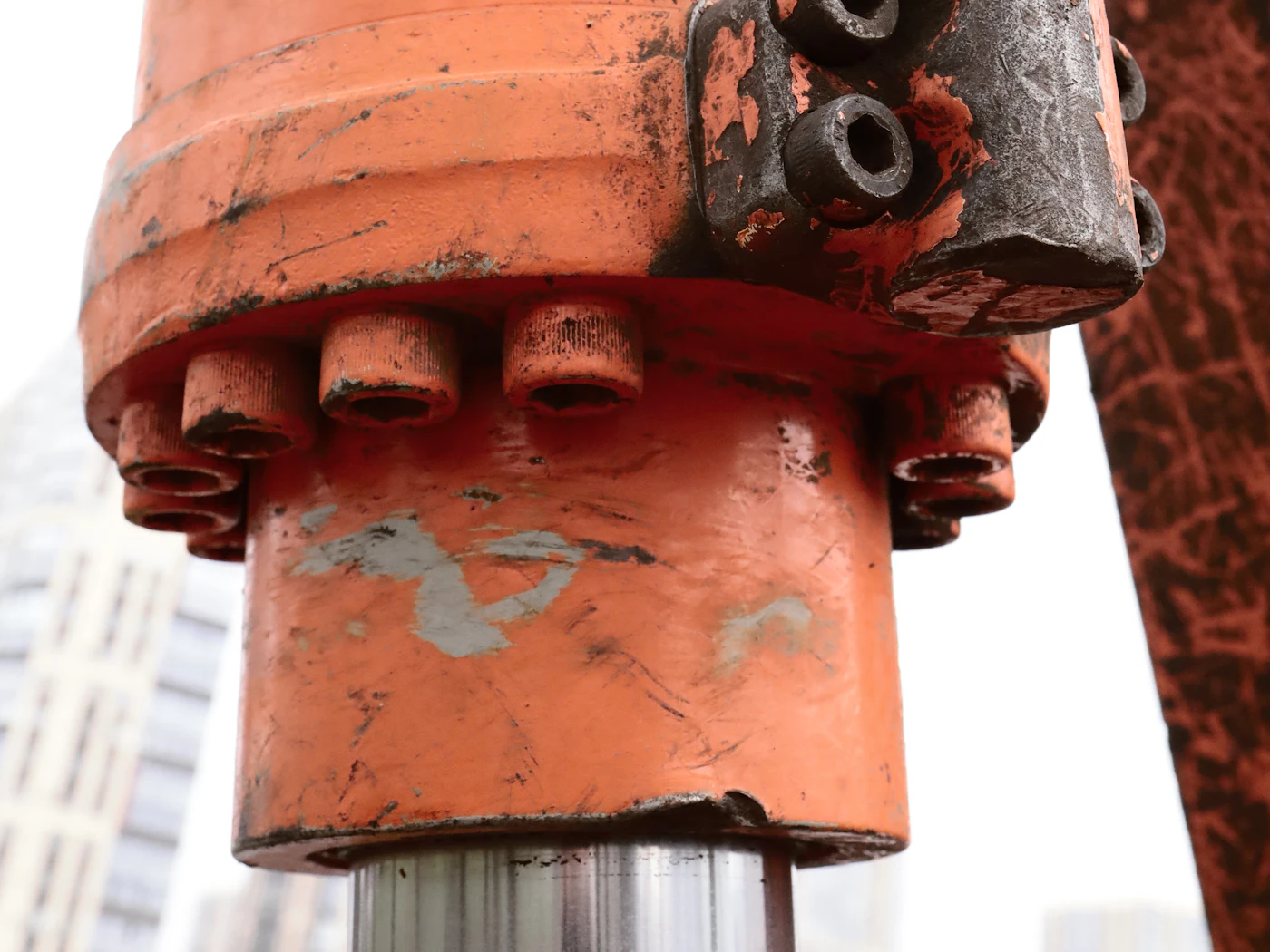 Närbild på en hydraulcylinder med flänsbultar och slanganslutning